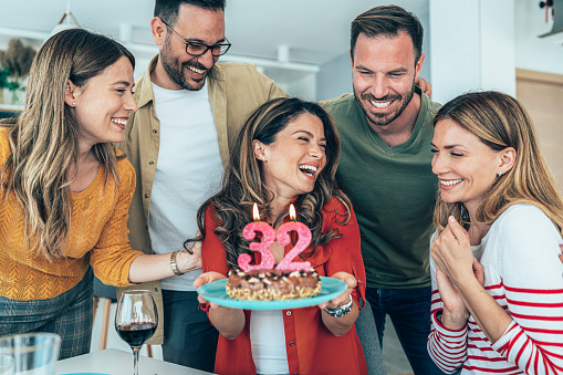 Young woman celebrating her 32nd birthday with friends at home