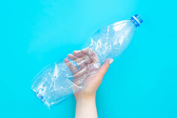 istock Used plastic bottle in a female hand on a blue background, top view. 1479046253