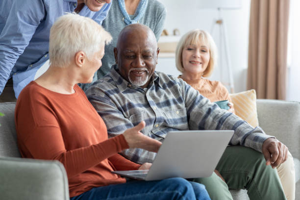 istock Cheerful elderly people spending time together at home, using laptop 1479048621