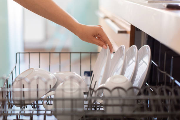 Closeup Shot Of Female Hand Loading Dishes To Dishwasher Machine In Kitchen Closeup Shot Of Female Hand Loading Dishes To Dishwasher Machine In Kitchen, Unrecognizable Woman Using Modern Electronic Equipment For Cleaning While Making Domestic Chores At Home, Side View dishwasher stock pictures, royalty-free photos & images