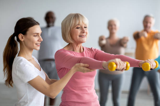 istock Young lady coach helping senior woman while exercising 1479050374