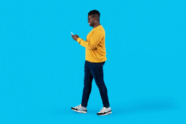 istock Young Black Man Walking With Smartphone In Hands Over Blue Studio Background 1479050731