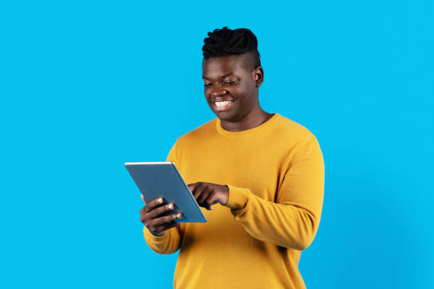 istock Smiling African American Male Using Digital Tablet While Standing Over Blue Background 1479050751
