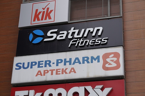Poznan, Poland – December 11, 2022: A closeup shot of Saturn Fitness and Super Pharm logos on the Galeria Malta shopping mall building