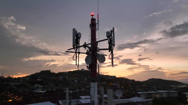 Cell Tower Silhouetted Against The Evening Sky Close-Up Drone Footage In City