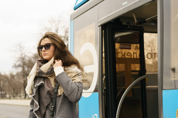 Moscow, Russia - March 22, 2023: Photography of the blue bus at bus stop in day. Young woman get off the bus. Lifestyle of big city concept. Modern female fashion. Street photography