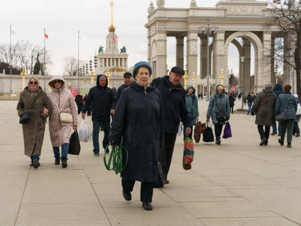 モスクワ、ロシア- 2023年3月22日:ストリート写真。年配の女性は春の日��に公共公園vdnkhを去ります。ライフスタイルのコンセプト。 - vdnk ストックフォトと画像