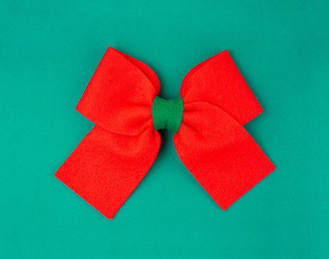 Red gift bow on green background.