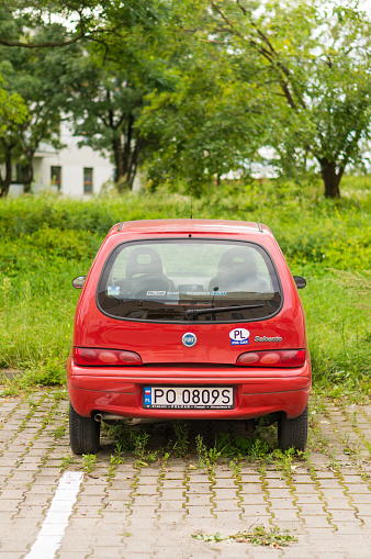 Poznan, Poland – August 12, 2017: Red Fiat Seicento parked on a parking spot with green weeds