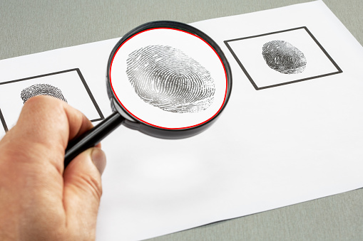Male Hand With Magnifying Glass Over Finger Print. Identity Search.
