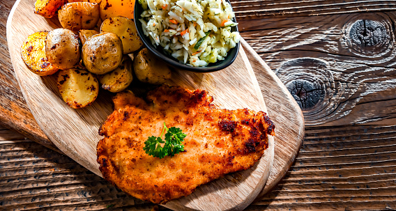 Chicken cutlet coated with breadcrumbs served with potatoes and cabbage