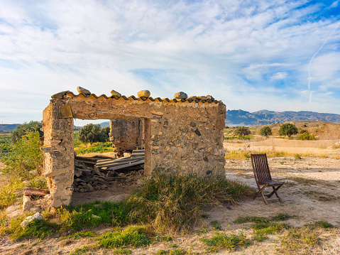 Ruined abandoned farmhouse in the countryside with blue sky and white clouds in Vera (Almería).