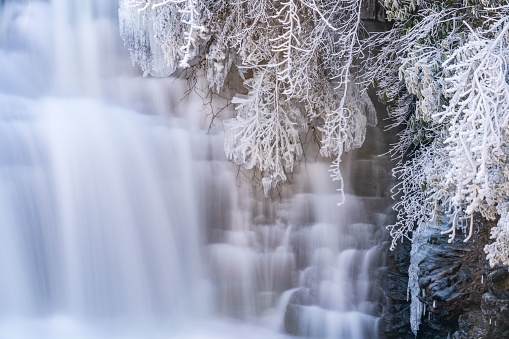 Tranquil winter scene of the Desoto Falls cascading over a rocky outcrop in a frosty forest, Alabama