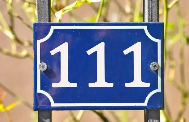 Photo of Blue house number plaque, showing the number hundred and eleven (111)