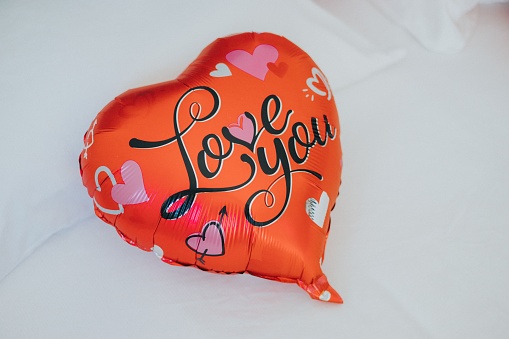 A red balloon with love you written on it on white background