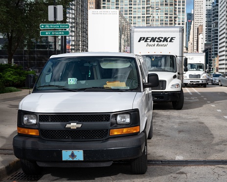 Chicago, United States – September 07, 2022: A white van and a a Penske rental truck in the backdrop on the road in an urban setting of Chicago