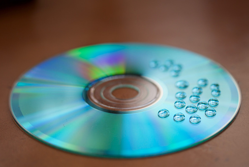 A selective focus shot of water drops on a blue compact disc