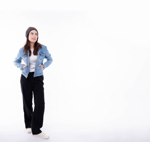 cool hipster young woman wearing denim jacket beanie hat in winter happy female university student looking at copy space smiling happily isolated on white background pretty girl wear sneakers shoes - women young adult isolated length imagens e fotografias de stock