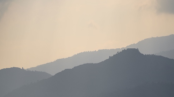 The silhouette of forested hills against the sunset sky