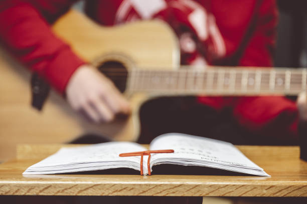 istock Person playing the guitar with note sheets on the table under the lights 1479080322