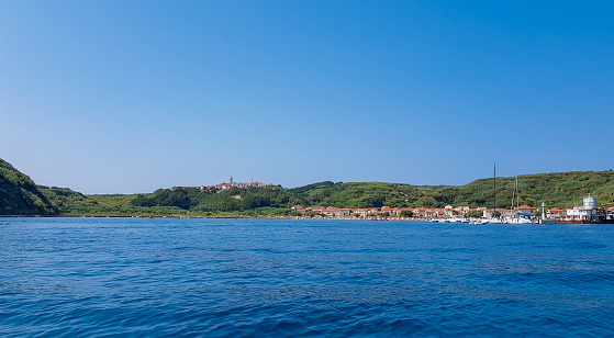 Idyllic small town on green island. Sea, summer, vacation, travel. People on beach on sunny day. Susak island, Croatia.