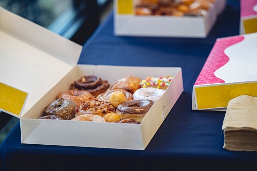 An assortment of freshly baked doughnuts on the tabletop, sprinkled with sugar and other toppings.