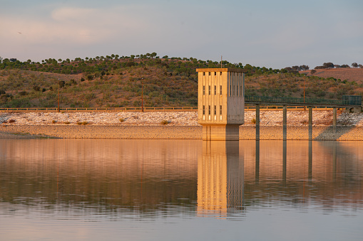 Lucefecit Dam in Terena with reflection on the lake reservoir at sunset, in Portugal