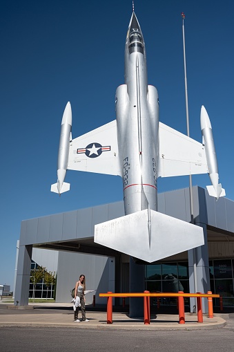 Weatherford, United States – September 15, 2022: A vertical image of a woman standing in front of the Stafford Air & Space Museum, smiling with a look of admiration