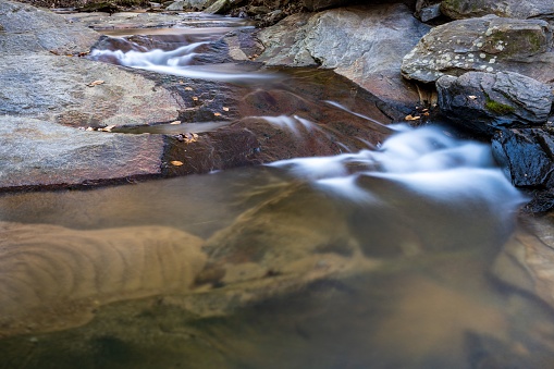 A crystal-clear stream of water cascades over a rocky ledge