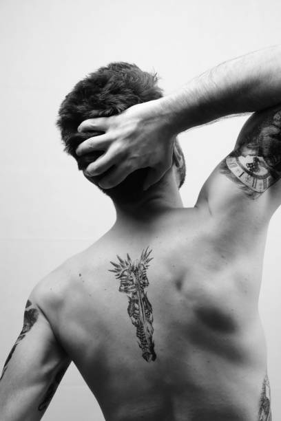 Back view of Undressed Fit Man Praying hoping hands up with tattoo on his back