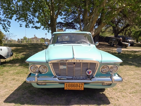 San Isidro, Argentina – October 08, 2022: old 1962 Chrysler Plymouth Valiant V 200 compact four door sedan in a park. Front view. Grille. Nature, grass, trees. Autoclasica 2022 classic car sho