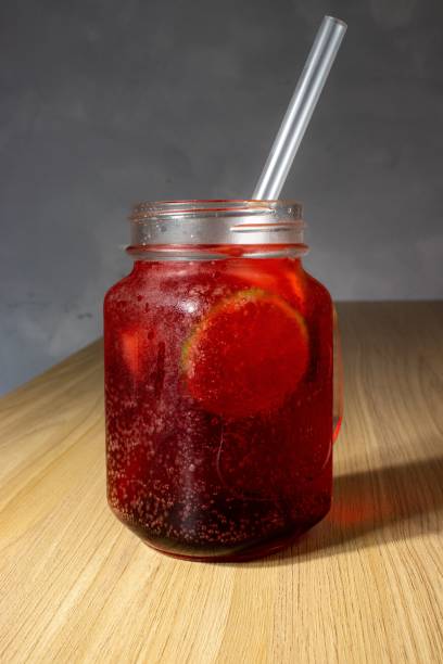 istock Canning jar filled with red tasty lemonade with a straw on a table top 1479091345