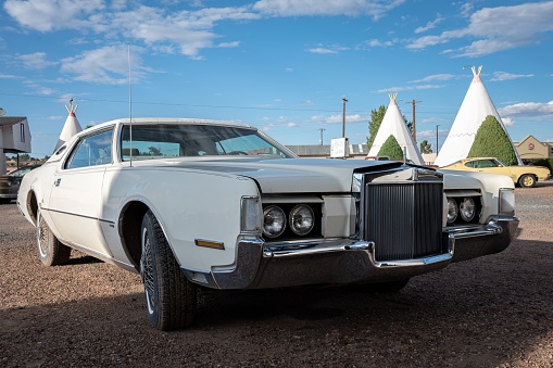 Holbrook, United States – September 07, 2022: A vintage white Lincoln Continental Mark IV car  parked in front of a wigwam motel