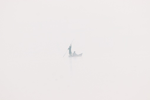 The two men in a boat on a foggy day.