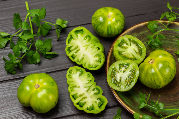 istock Parsley sprigs, green tomatoes in a plate and on the table. 1479096456