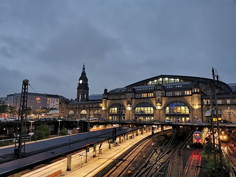 Light-filled evening view of Hamburg Hauptbahnhof with commuter trains on the tracks.
