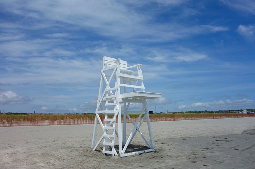 a white life saver's high chair on the sandy beach with blue sky