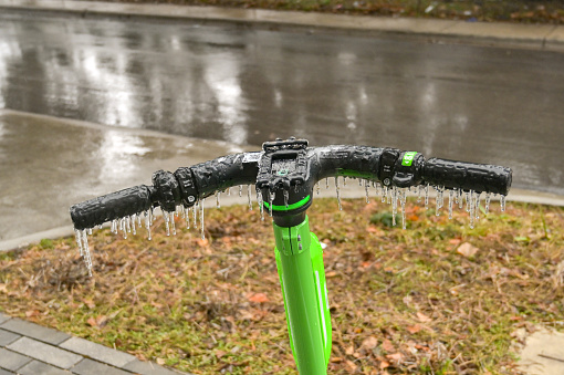 Austin, Texas, USA - February 2023: Icicles hanging off the handlebars of an electirc scooter after freezing rain fell on the city
