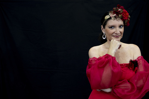 A female with a red Spanish dress and floral ornaments in her hair on an isolated background
