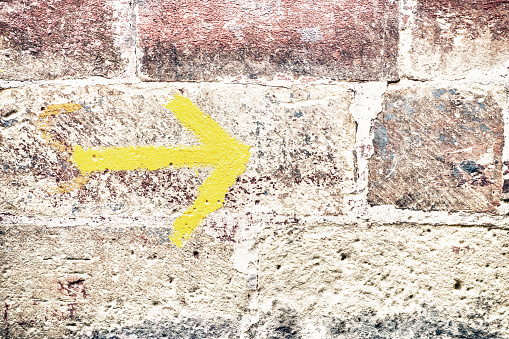 A yellow right arrow drawn on the brick wall
