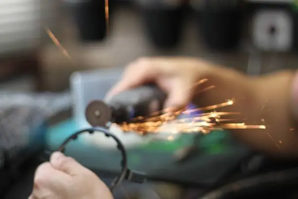 A person is using an angle grinder to shape metal, with sparks flying in the background