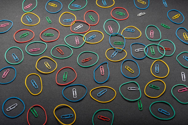 Background from stationery items. The background is slanted. Falling rubber bands and paper clips. On a black background.