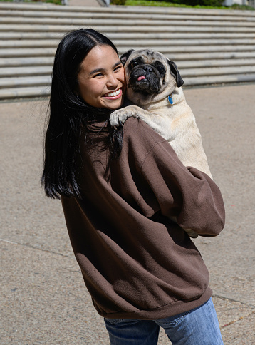 Young attractive Asian American celebrating college graduation with her little pug dog