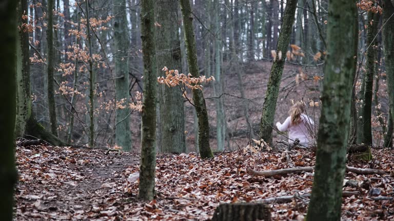 Young Caucasian Girl Running Away from Unknown Danger Through Autumn Forest