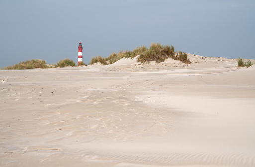A mesmerizing view of the sand dunes of Amrum with the lighthouse in North Frisia, Germany