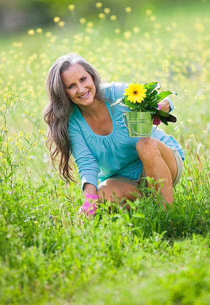 mais mulher jardinagem em campo de flores silvestres - planting clothing gray hair human age - fotografias e filmes do acervo