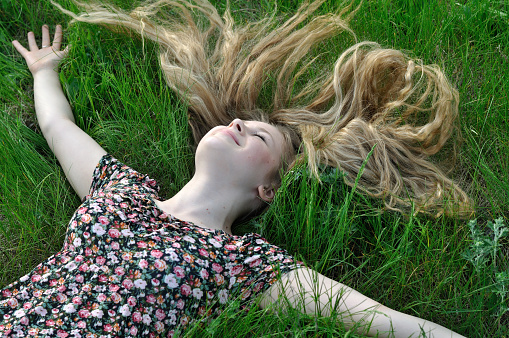teenage girl with long hair relaxing on the grass at summer day