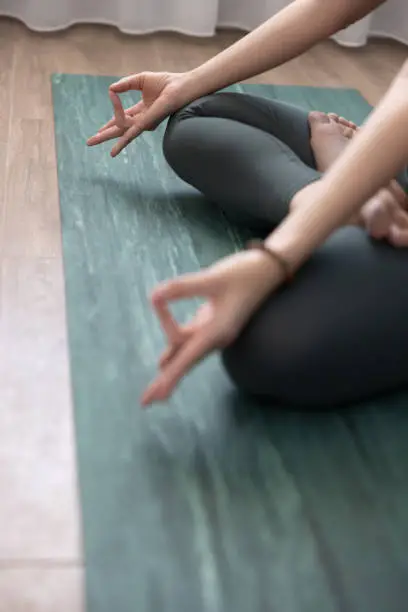 Selective focus of prithvi mudra executed in lotus position by a young woman.