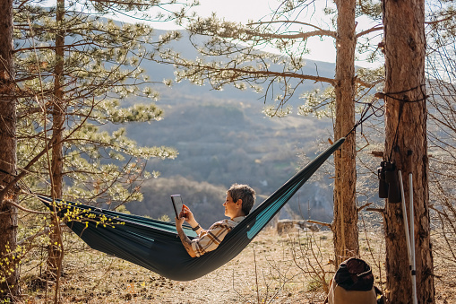 Woman working comfortably on her tablet while in a hammock.