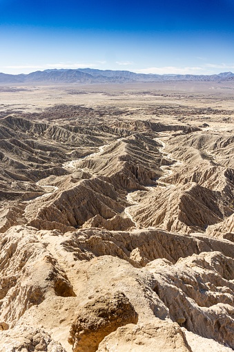 Aerial view of a vast desert landscape with sand dunes, hills, and valleys stretching out into the horizon